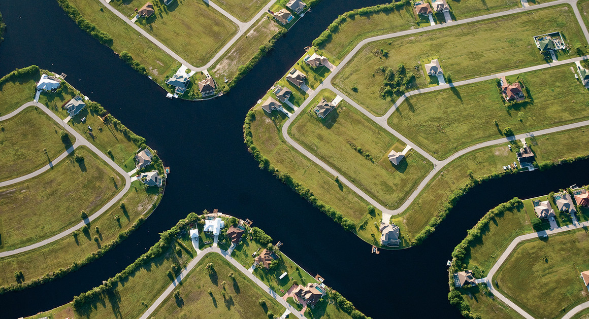 Aerial view of waterfront residential lots along winding canals, with green lawns and scattered homes